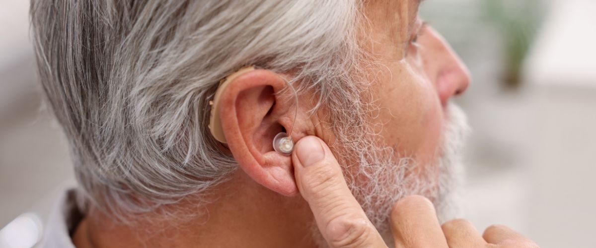 Älterer Mann setzt Im-Ohr-Hörgerät ein – moderne Hörgeräte bei Hörverlust